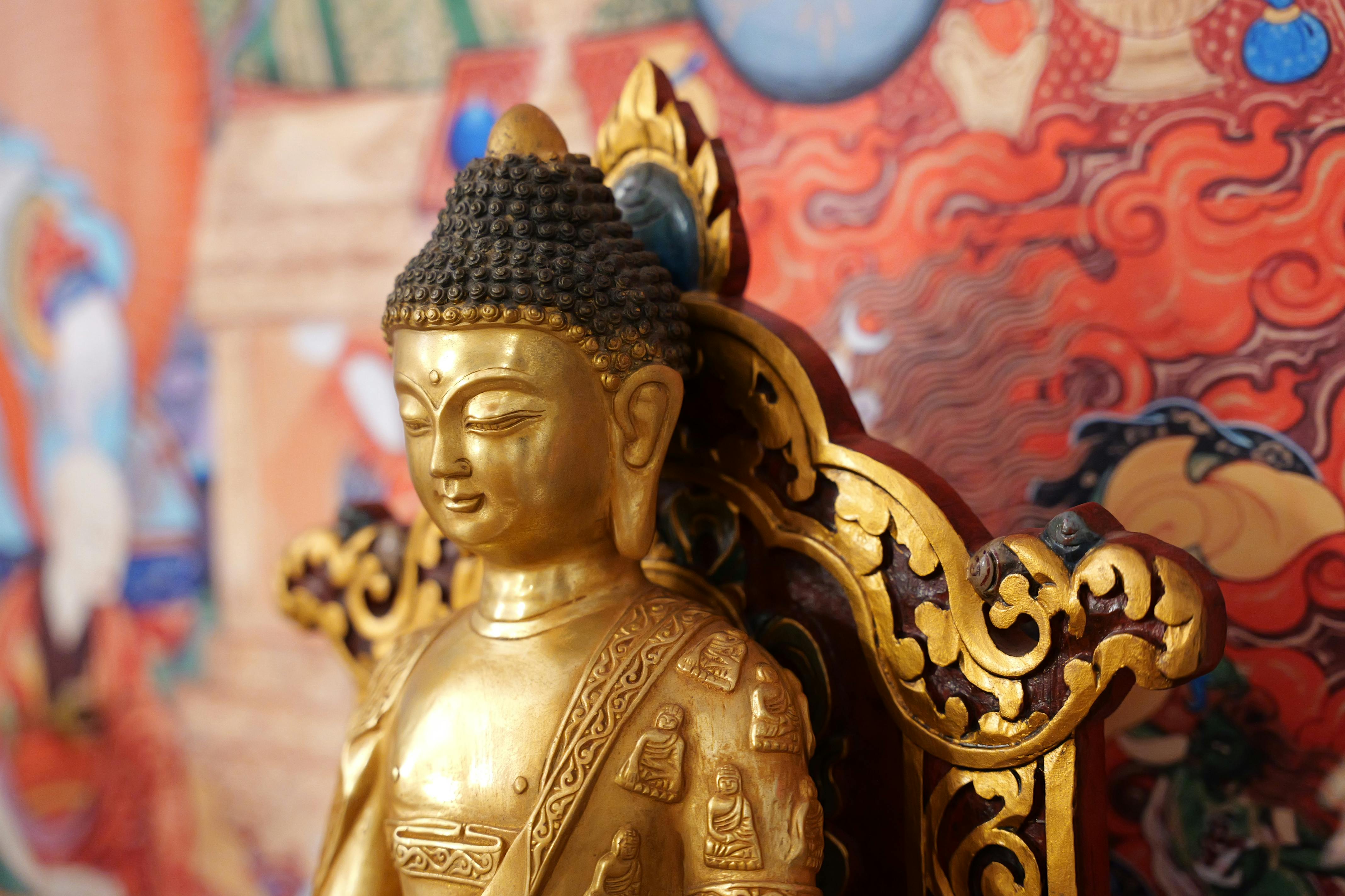 Close-up of a golden Buddha statue with ornate details against a vibrant background, depicting spirituality and art.