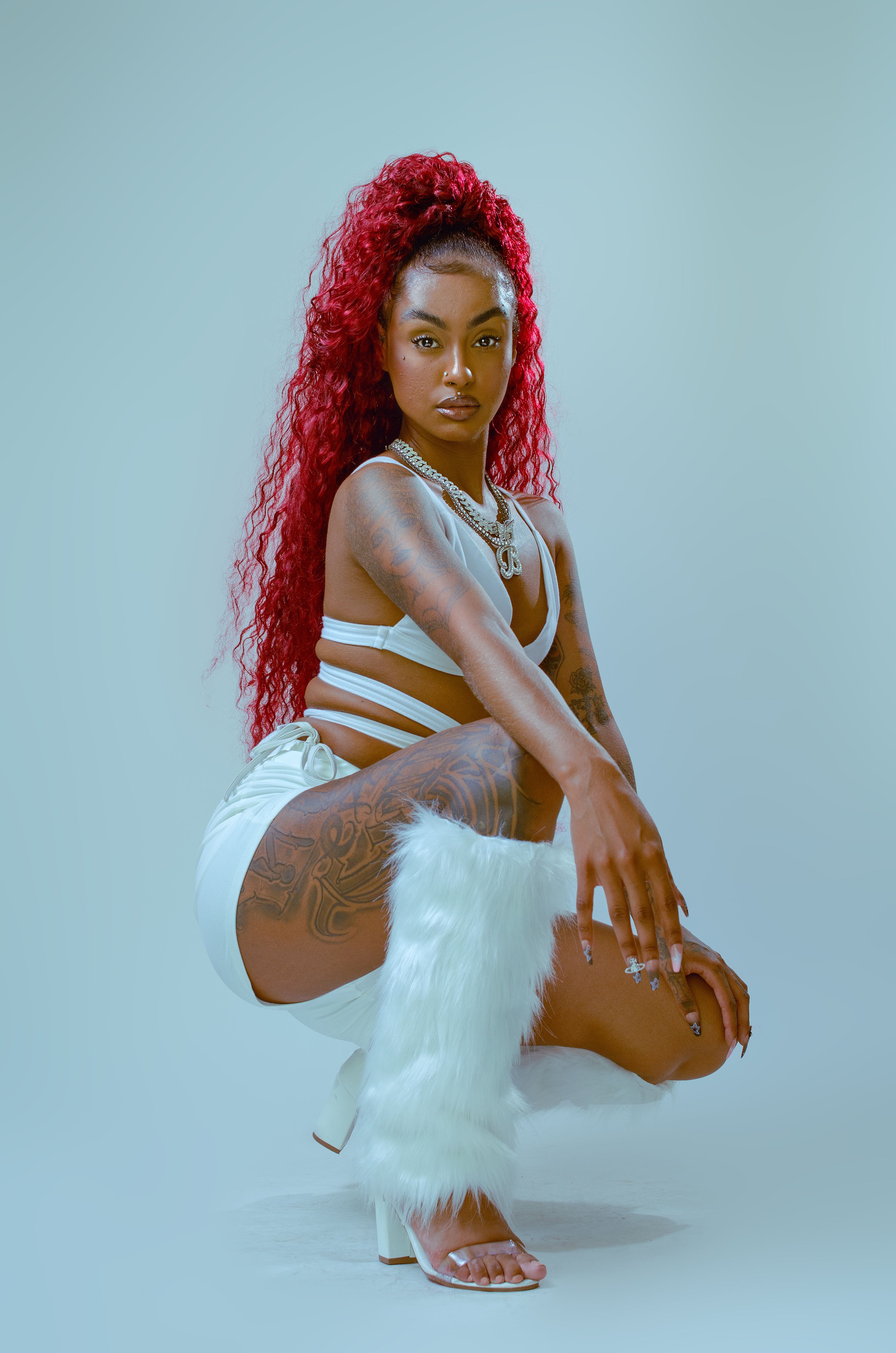 Striking fashion portrait of a woman with red hair in a stylish white outfit and boots.