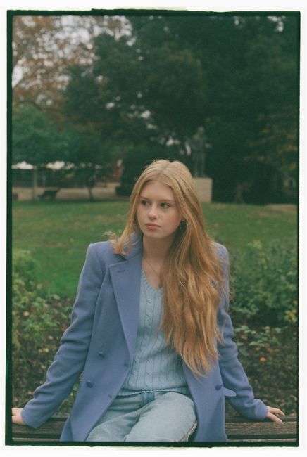 Stylish woman in blue blazer sitting on a park bench in Lisbon, Portugal.