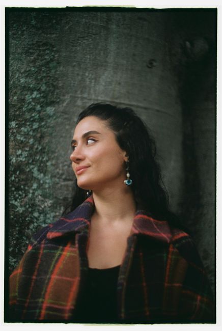 Portrait of a woman in a plaid coat enjoying a serene autumn day in Lisbon.