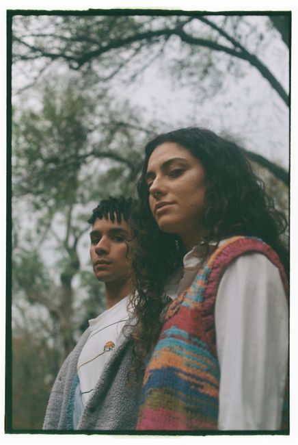 A fashionable young couple poses outdoors in a lush Lisbon park.