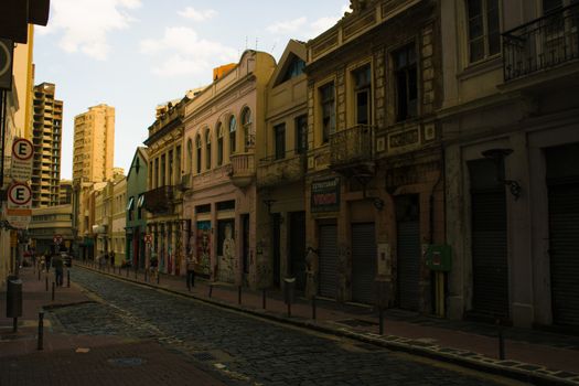Charming cobblestone street lined with colorful historic buildings in an urban setting.