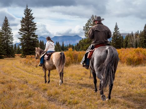 A man and woman horseback riders make their way along a trail in the Ya Ha Tinda Ranch area in Alberta, Canada during an autumn day