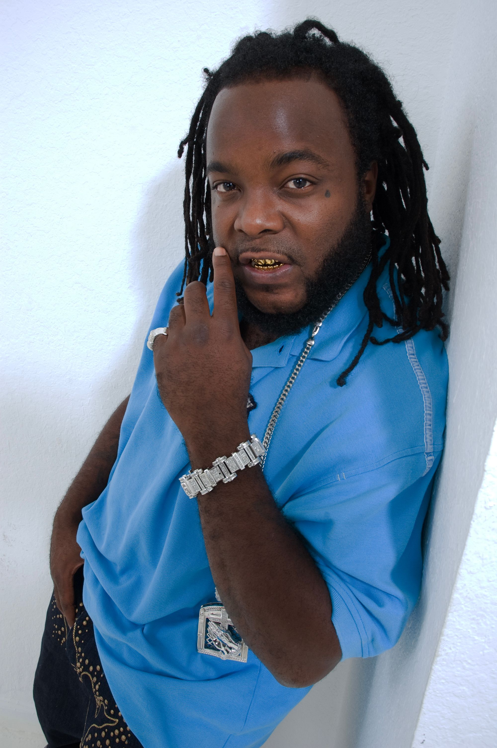 Confident man in blue shirt with dreadlocks, jewelry, in Tampa, FL.