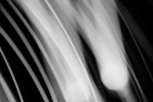 Abstract black and white image featuring dynamic light streaks creating a sense of motion and flow.