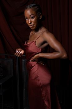 Stunning portrait of an elegant woman posing against a dark backdrop in a silk dress.