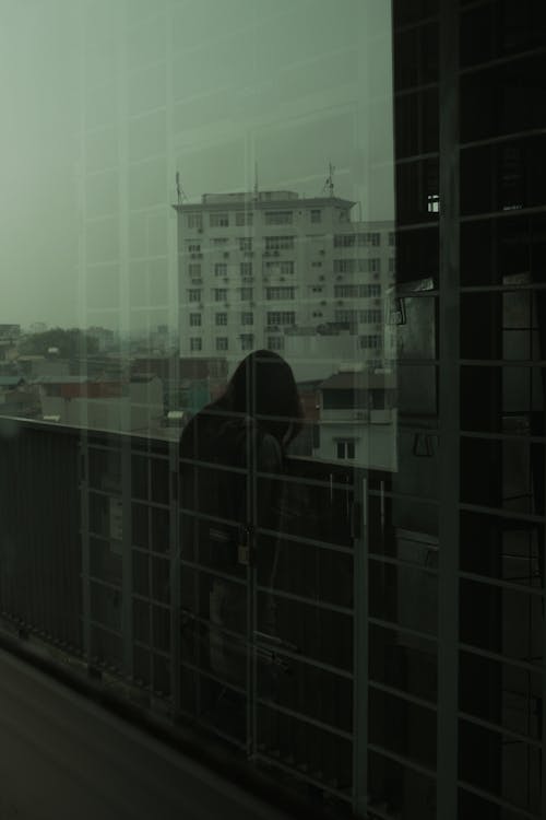 Free Reflection in the Window of a Person Standing on the Balcony Stock Photo