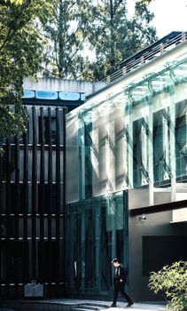 A sleek, modern glass building with sunlight and shadows in a city environment.