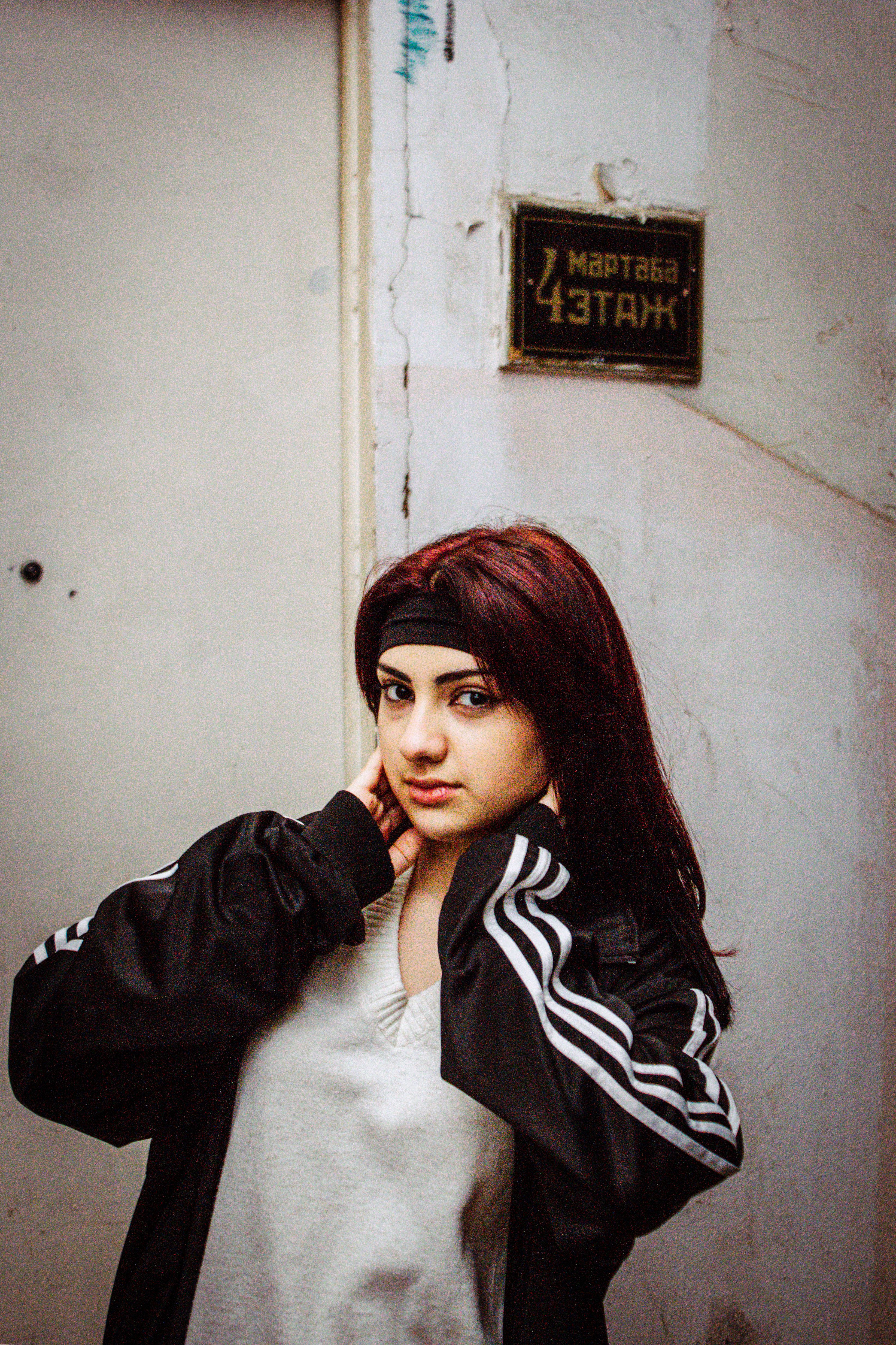 Portrait of a young woman in a tracksuit posing indoors by a staircase.