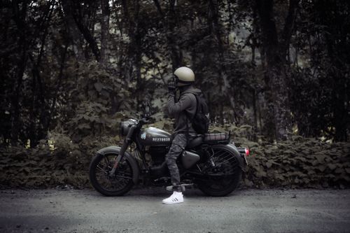 Free Man with helmet and backpack beside motorcycle in Indian forest. Stock Photo