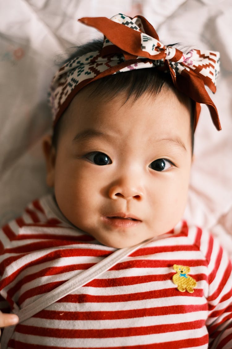 Little Girl Wearing Striped Shirt Lying In Bed 