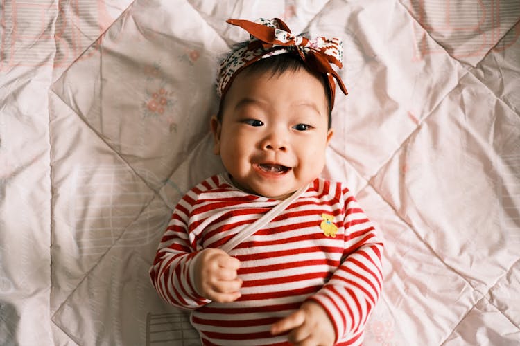 Little Girl Wearing Stripped Shirt On Bed 