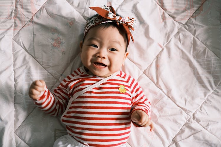 Little Girl Wearing Stripped Shirt On Bed 