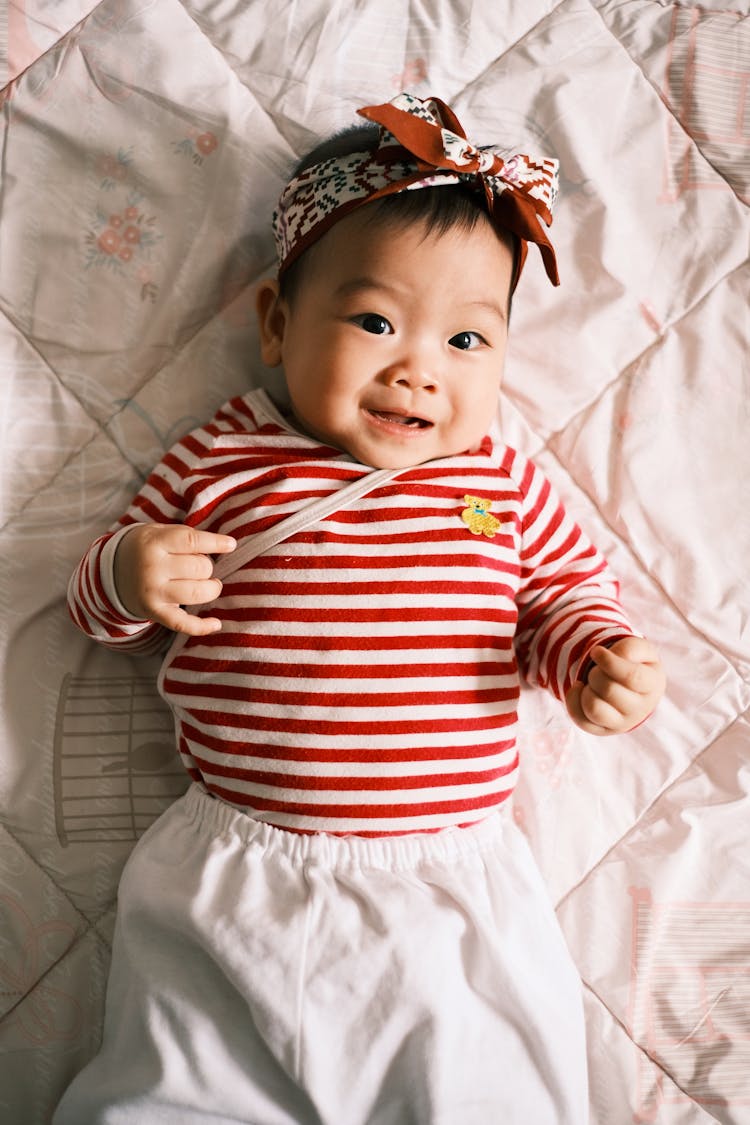 Little Girl Wearing Stripped Shirt On Bed 