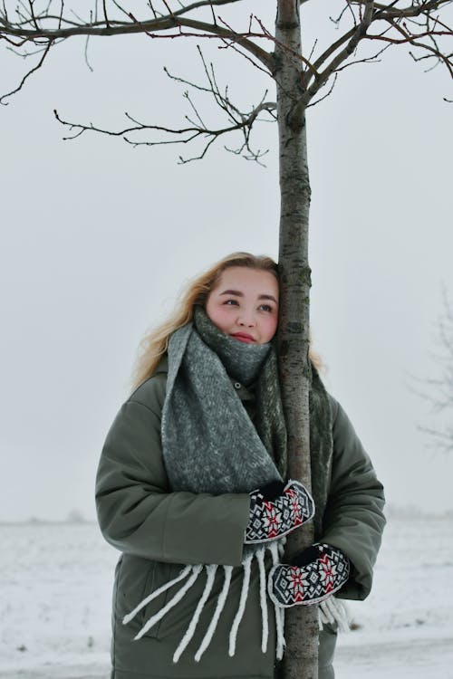 Blonde Woman in Jacket Holding Tree