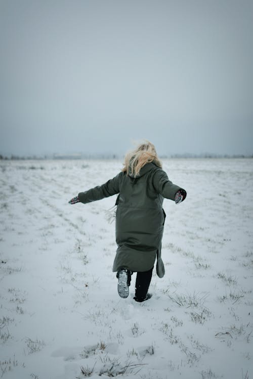 Woman in Coat Enjoying Field in Snow