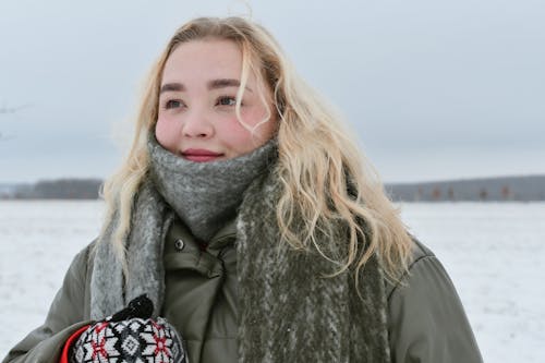 Portrait of a Young Woman in Winter Clothes on a Snow Covered Field
