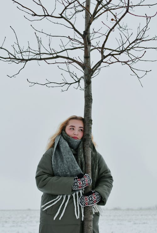 Woman in Jacket Holding Tree in Winter