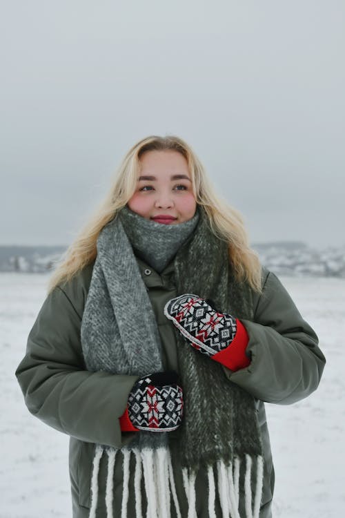 Woman in a Woolen Scarf and Knitted Mittens in a Snowy Field