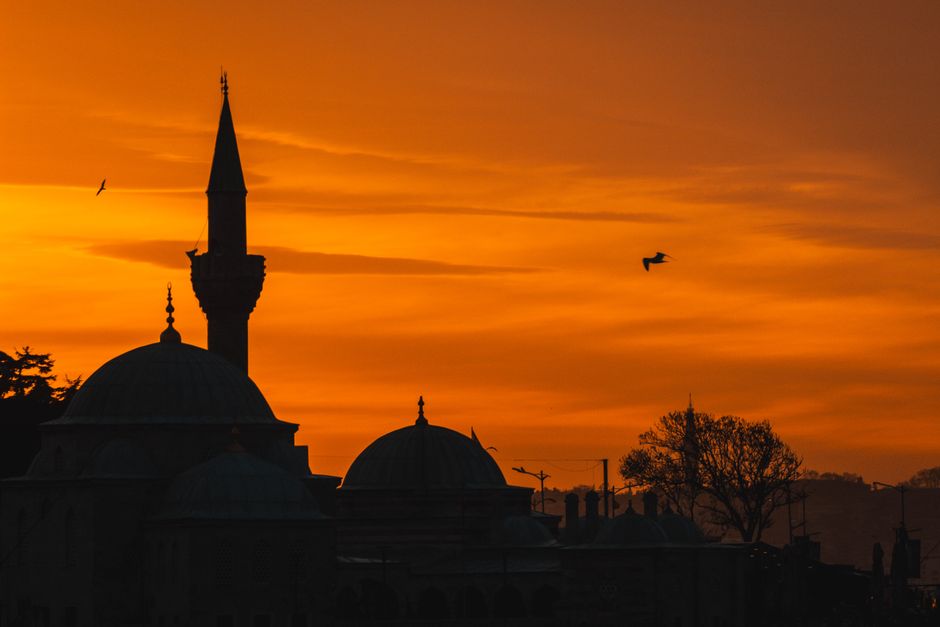 Dramatic silhouette of the Üsküdar Mosque's minaret against a vibrant sunset sky in Istanbul, Turkey.