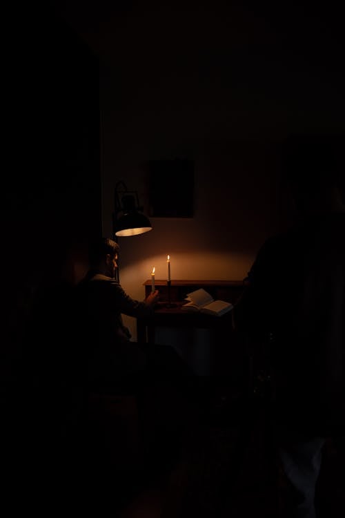 Sitting Man by Desk Illuminated with Candles