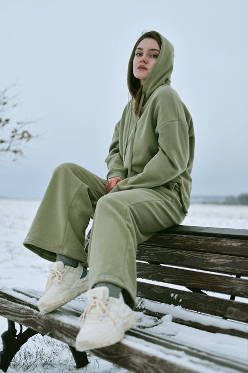 Woman in Green Hoodie Sitting on Bench in Winter