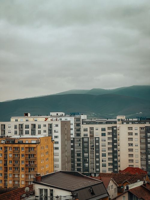 Free High-rise apartment blocks against a mountain under an overcast sky, showcasing urban residential life. Stock Photo