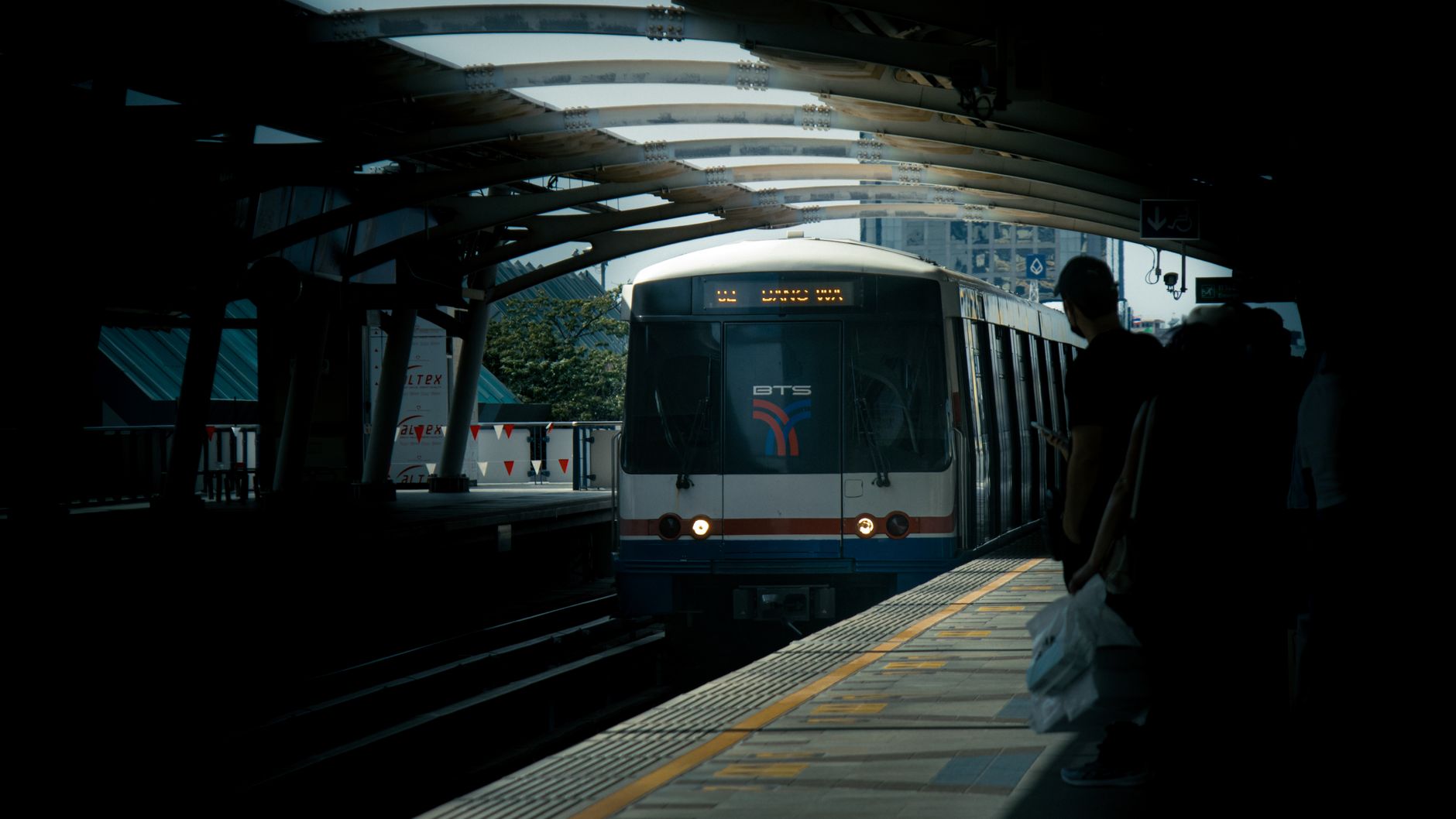 BTS Skytrain train arriving at an elevated station in central Bangkok