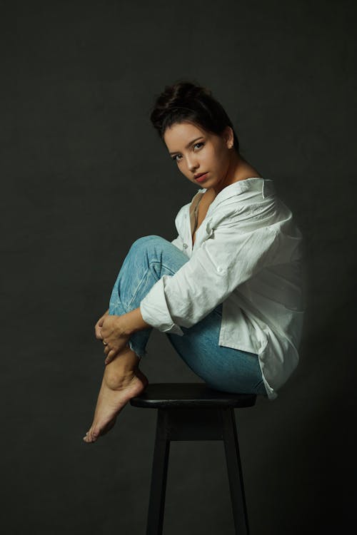 Brunette Woman in White Shirt and Jeans Posing on Stool