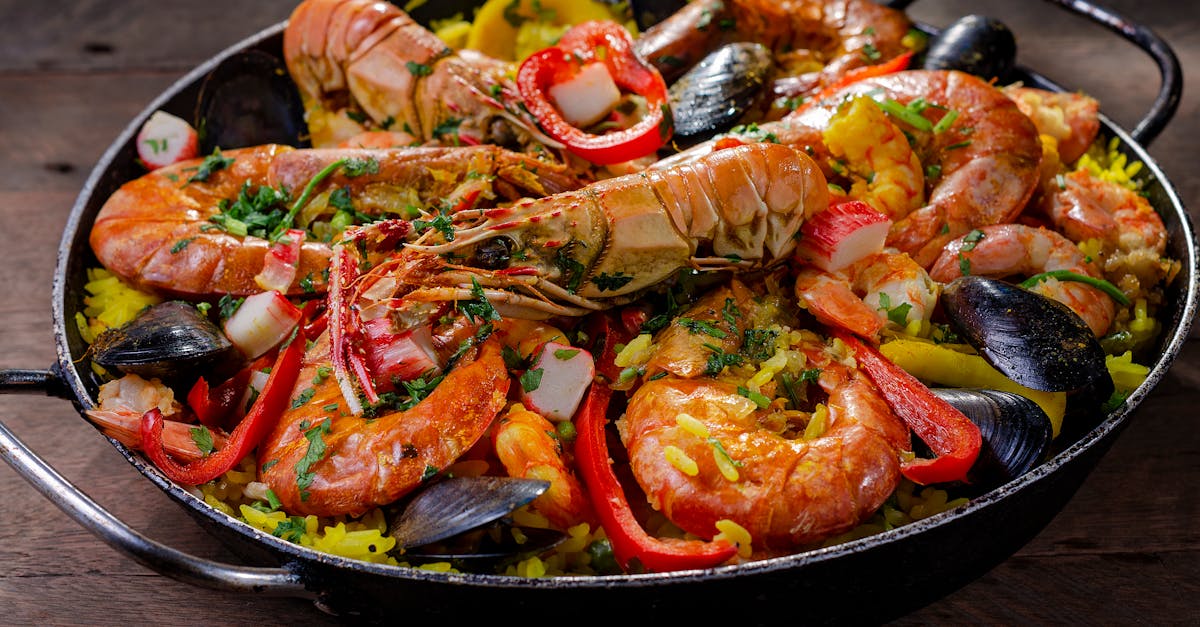 A traditional Spanish paella dish being cooked outdoors over an open flame in a large paella pan.