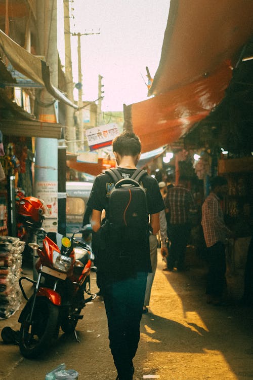 Man with Backpack Walking Down Narrow Alley in Town