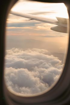 View from an airplane window showing clouds and sunrise, perfect for travel enthusiasts.