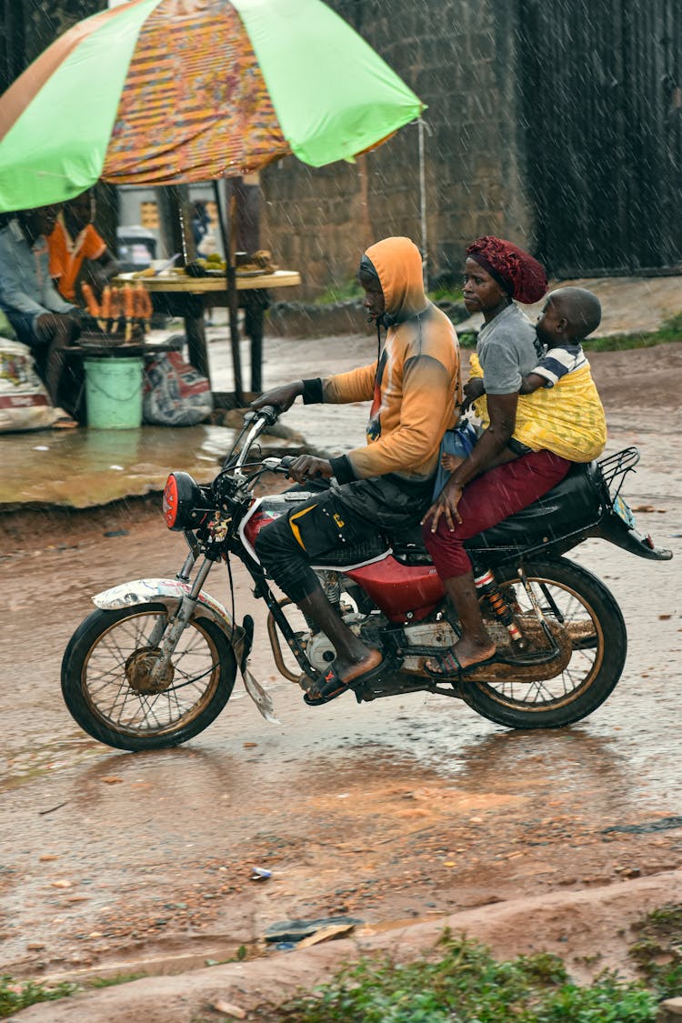 A Family Riding On A Motorcycle In The Rain 