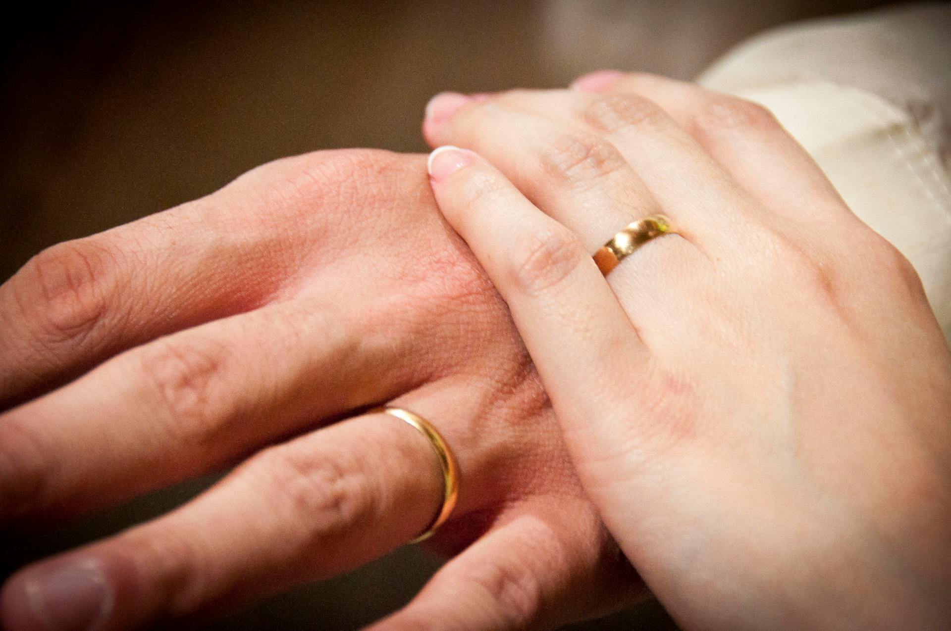 A touching close-up of newlyweds' hands showcasing their gold wedding bands.