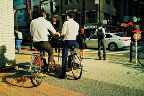 Free Business people biking through lively Tokyo streets during a sunny day. Stock Photo