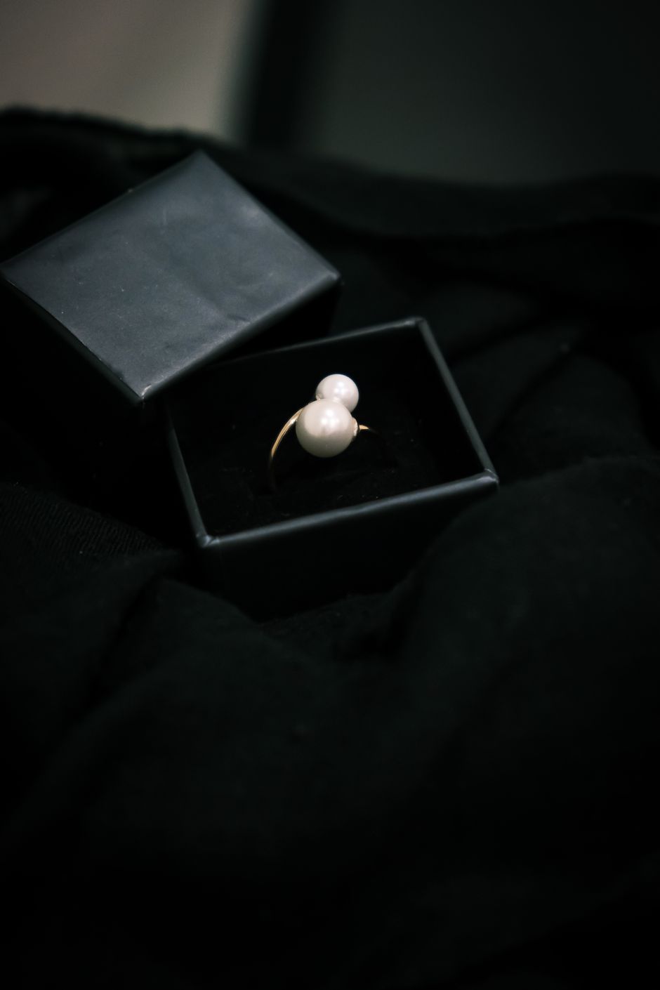 A luminous pearl ring in a black velvet ring box