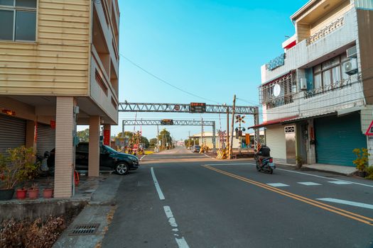 A peaceful urban street with buildings and a motor scooter passing by.