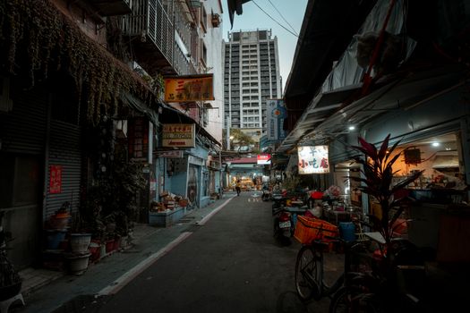 Explore an urban alley with market stalls and cityscape backdrop during dusk, a blend of tradition and modernity.