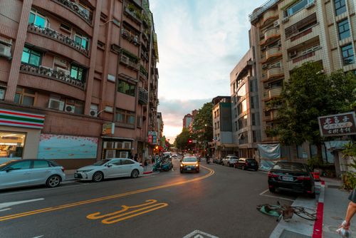 Free A vibrant city street with cars and buildings at sunset, showcasing urban life. Stock Photo