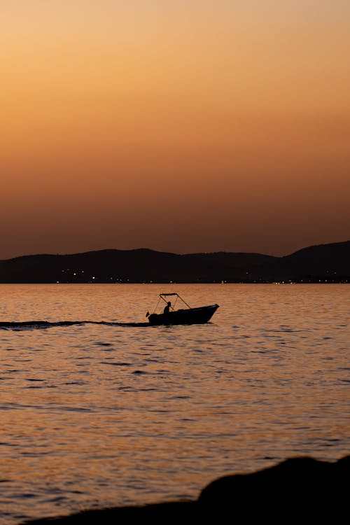 A Silhouetted Boat near the Shore at Sunset