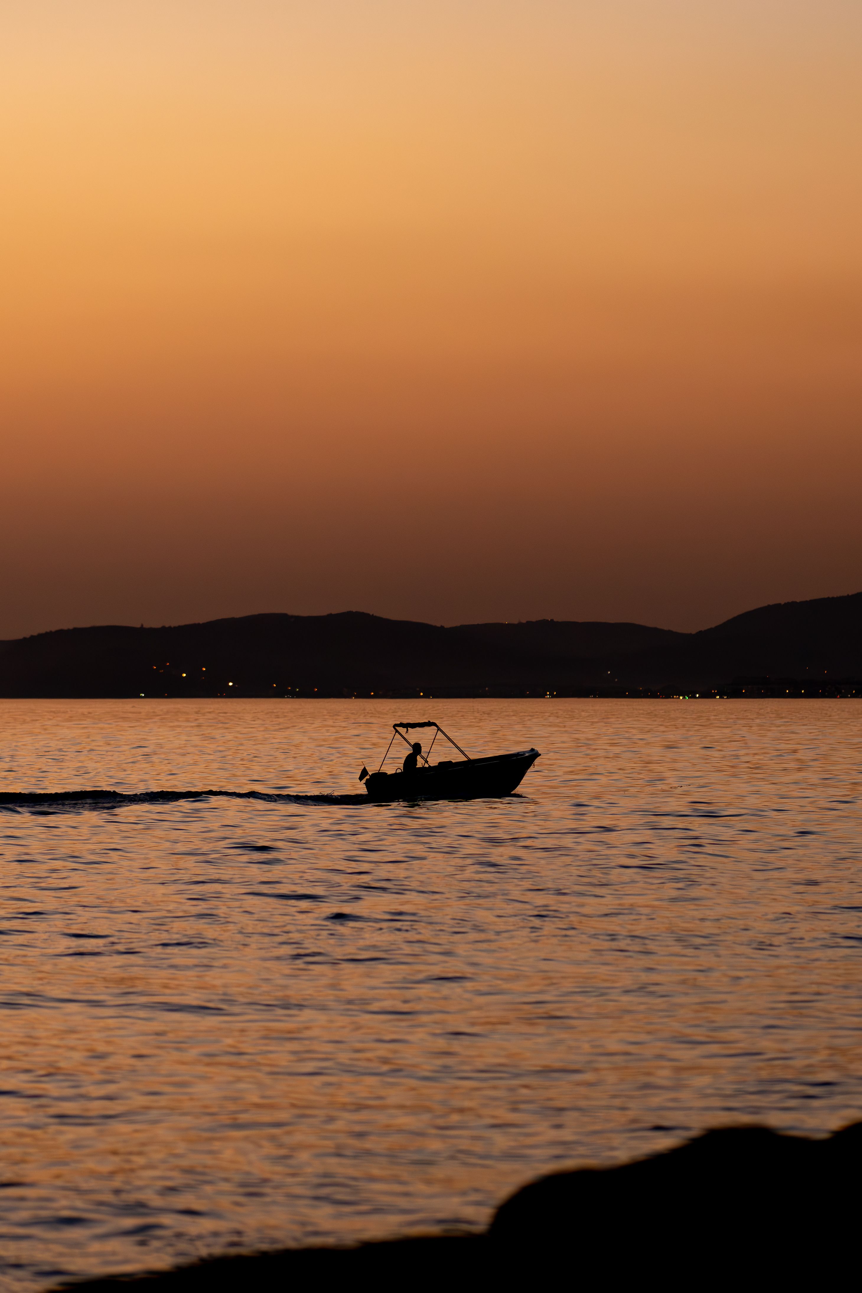 A Silhouetted Boat near the Shore at Sunset · Free Stock Photo