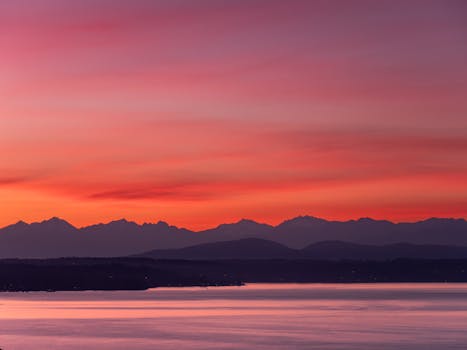 Capture of the vibrant sunset over Seattle's Olympic Mountains with a serene water view.
