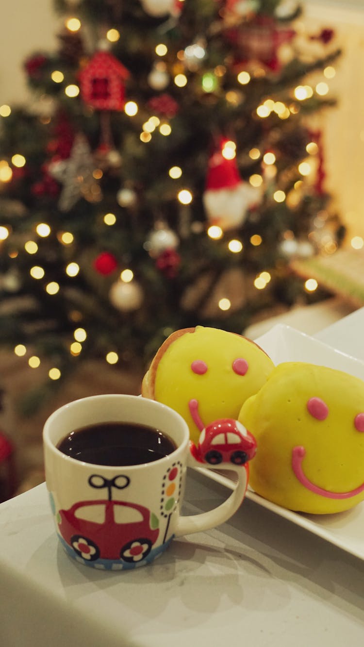 A Cup Of Tea And Cakes On The Table With The Christmas Tree In The Background 