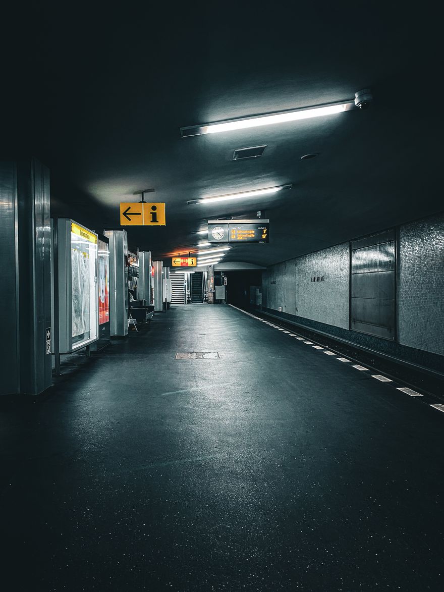 Peron de metrou din Berlin iluminat noaptea, cu indicatoare luminoase