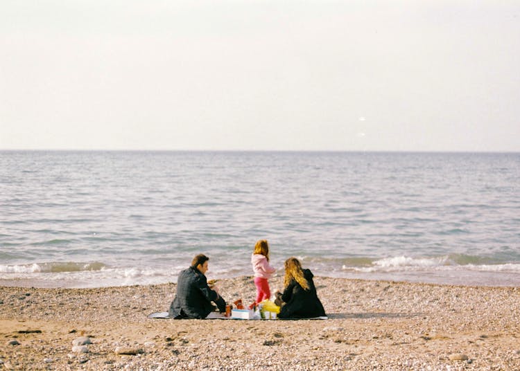 Mother And Father With Daughter On Beach On Sea Shore