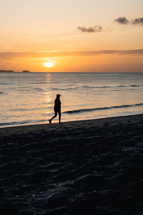 Person Walking on the Beach at Sunset