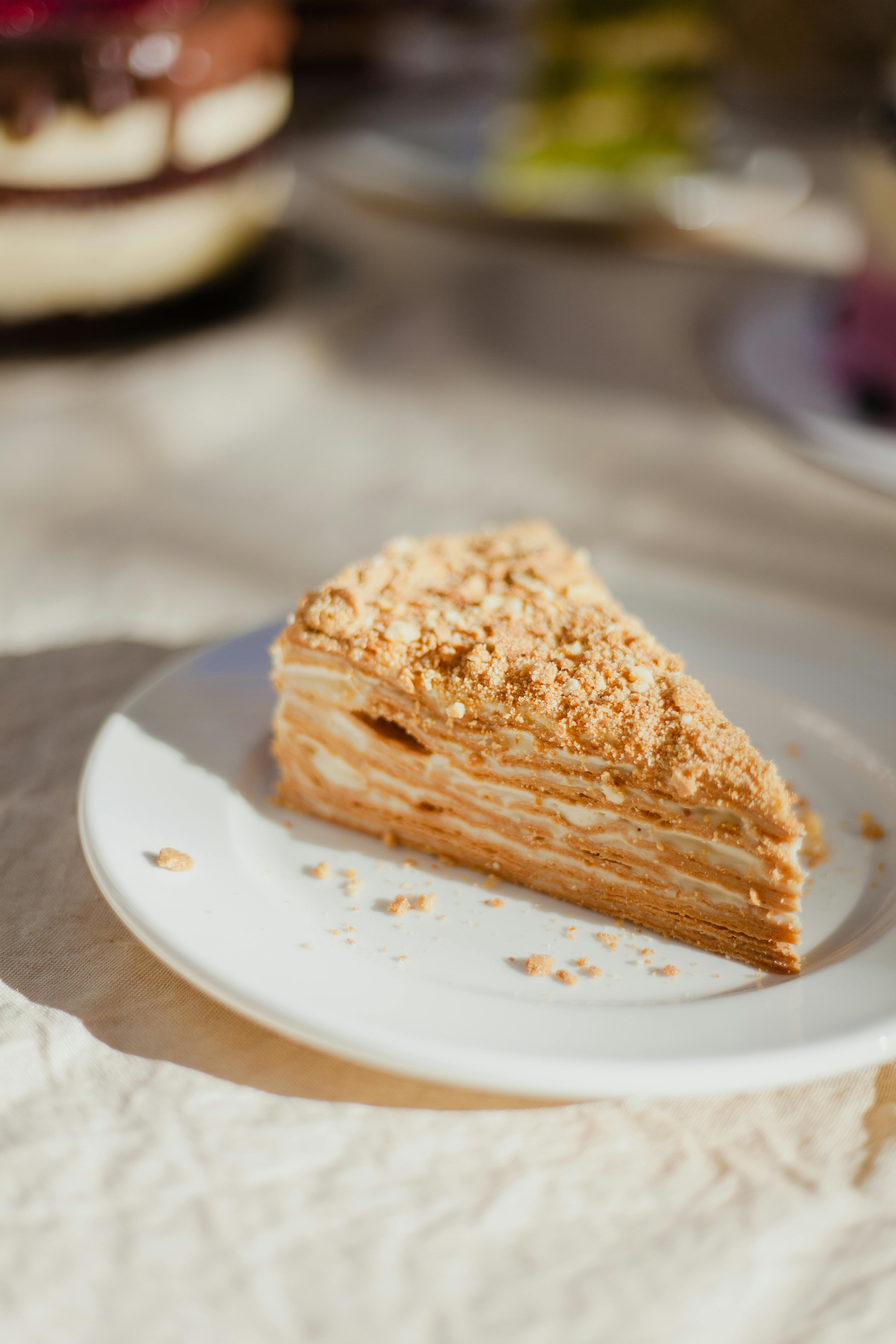 Delicious slice of layered cake with crumbles served on a plate in natural daylight.
