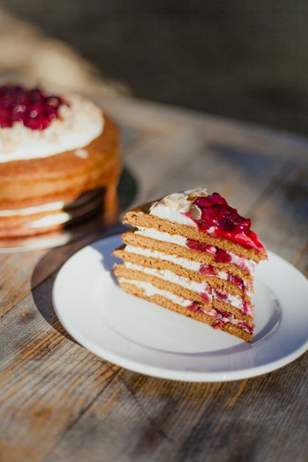 Close-up of a layered cake slice topped with fresh berries on a white plate.
