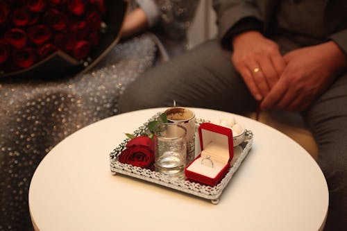 A Man and Woman Sitting at a Table with a Decoration and an Engagement Ring in a Box 