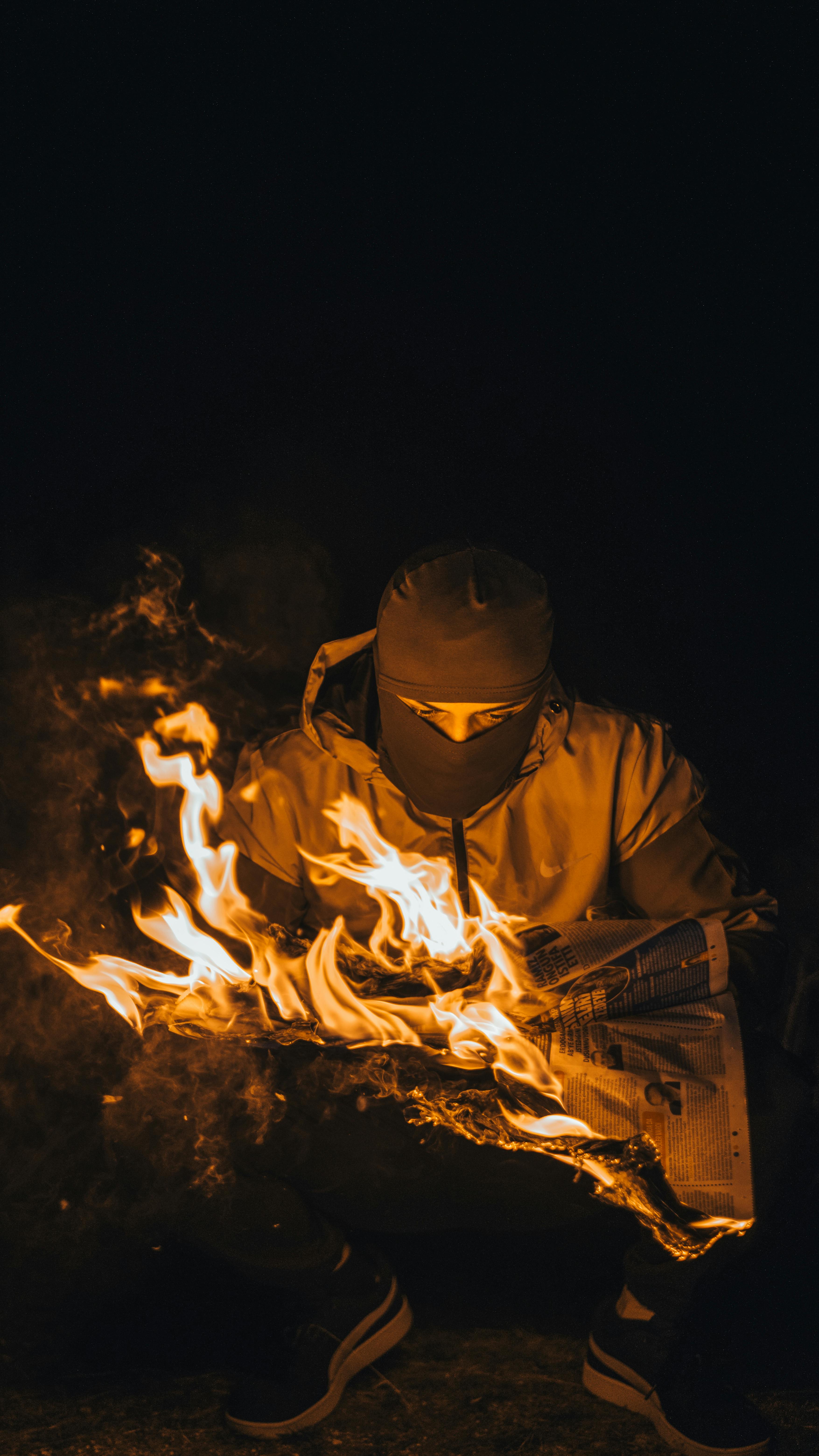 Foto de stock gratuita sobre ardiente, fuego, hombre, llamas, noche,  pasamontañas, periódico, sujetando, tiro vertical